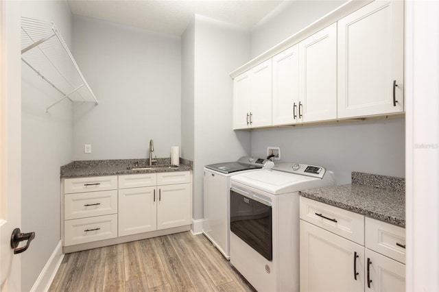 washroom with cabinets, light hardwood / wood-style flooring, washing machine and clothes dryer, and sink