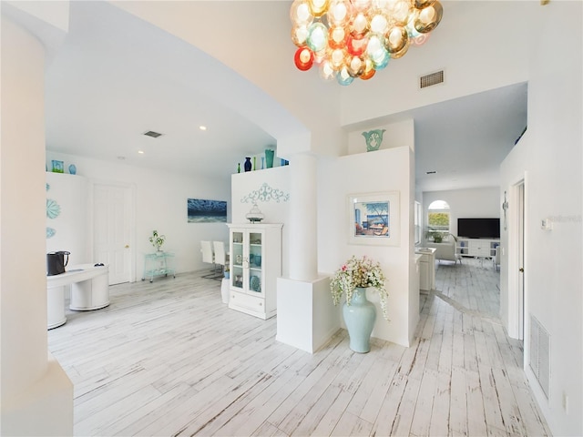 hallway with a notable chandelier and light hardwood / wood-style floors