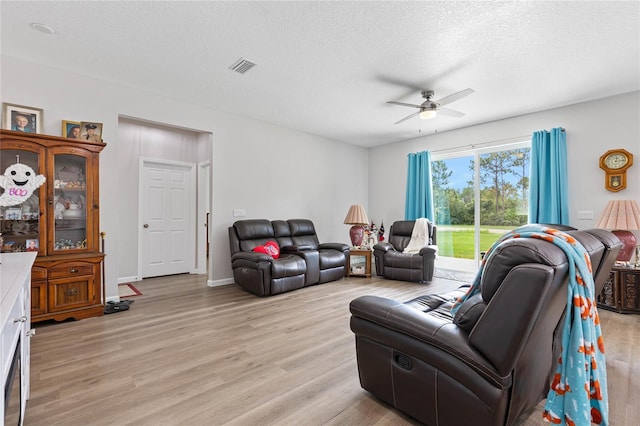 living room featuring ceiling fan, a textured ceiling, and light hardwood / wood-style floors