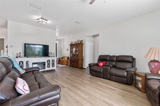 living room with light wood-type flooring, a textured ceiling, and ceiling fan