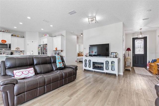 living room featuring light hardwood / wood-style flooring and a textured ceiling