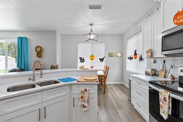 kitchen featuring appliances with stainless steel finishes, white cabinetry, sink, and a wealth of natural light