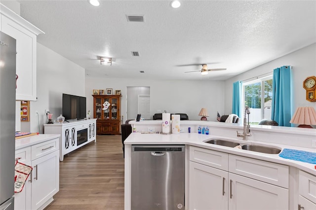 kitchen with a textured ceiling, dark hardwood / wood-style floors, sink, white cabinetry, and stainless steel dishwasher