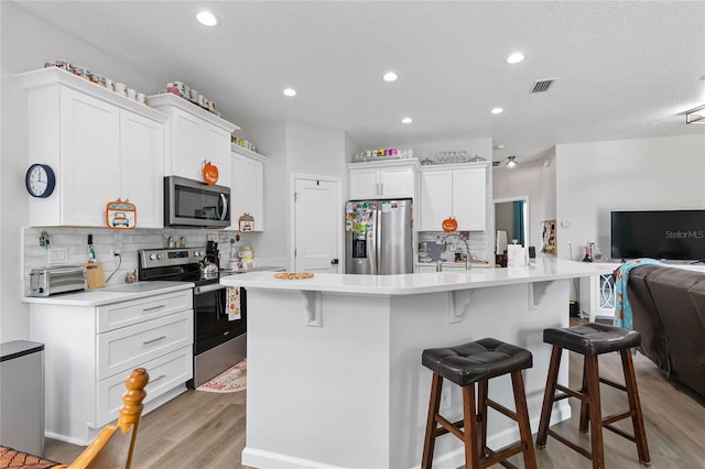 kitchen with appliances with stainless steel finishes, a center island with sink, and a kitchen bar