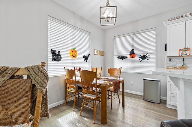 dining space with light wood-type flooring, a chandelier, and plenty of natural light