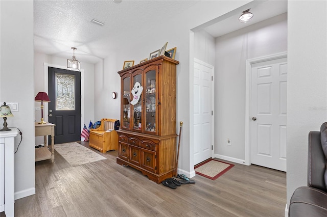 entryway featuring a textured ceiling and light hardwood / wood-style flooring