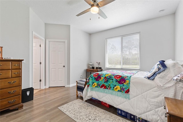 bedroom with ceiling fan, a textured ceiling, and light hardwood / wood-style floors