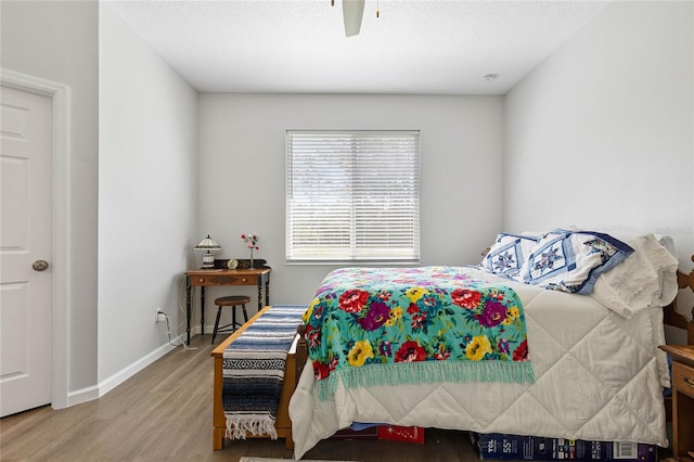 bedroom with ceiling fan, hardwood / wood-style flooring, and a textured ceiling