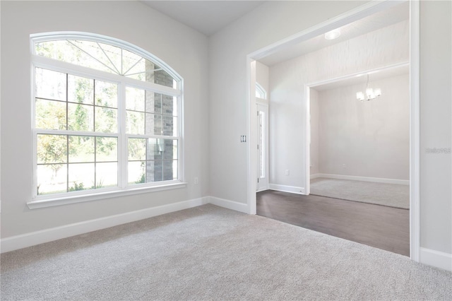 empty room with carpet floors, a notable chandelier, and plenty of natural light