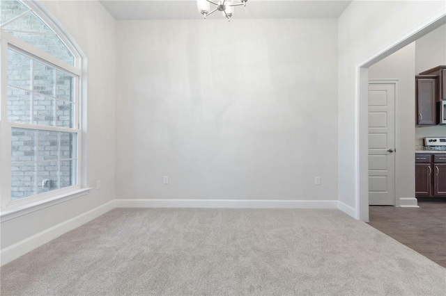 carpeted spare room featuring a notable chandelier