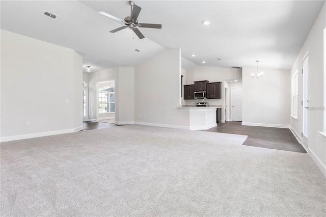 unfurnished living room with dark carpet, ceiling fan with notable chandelier, and lofted ceiling