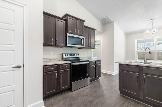 kitchen with appliances with stainless steel finishes, vaulted ceiling, dark wood-type flooring, dark brown cabinets, and sink