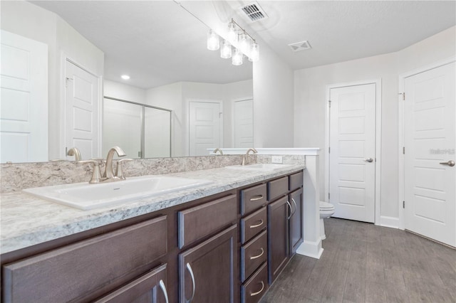 bathroom with hardwood / wood-style floors, vanity, toilet, and a shower with shower door