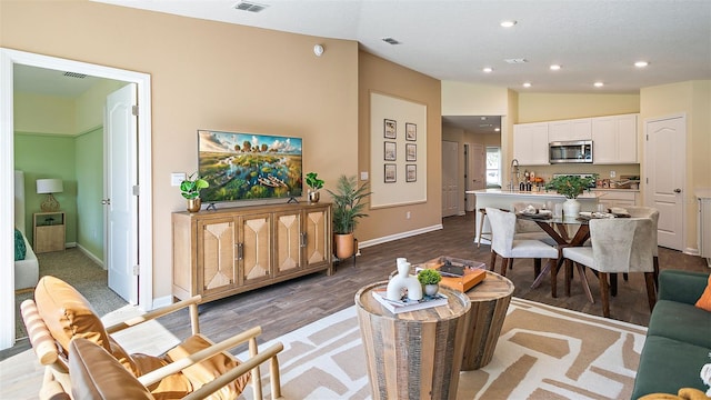 living room featuring lofted ceiling, hardwood / wood-style flooring, and sink