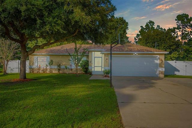 ranch-style home featuring a garage and a yard