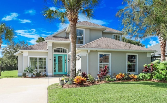 12 S Lakewalk Dr, Palm Coast, FL 32137 - traditional-style house featuring stucco siding, a front yard, a shingled roof, and concrete driveway