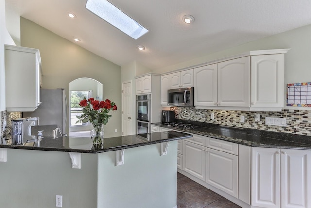 12 S Lakewalk Dr, Palm Coast, FL 32137 - kitchen with a peninsula, appliances with stainless steel finishes, white cabinetry, decorative backsplash, and lofted ceiling