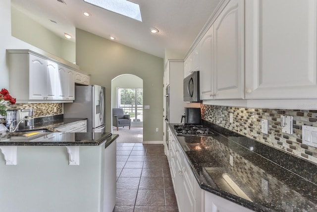 kitchen with dark stone countertops, appliances with stainless steel finishes, backsplash, and white cabinetry