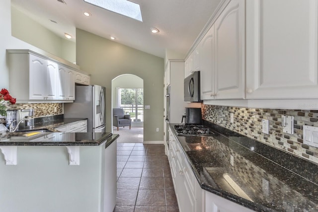 12 S Lakewalk Dr, Palm Coast, FL 32137 - kitchen featuring stainless steel appliances, arched walkways, a peninsula, a kitchen breakfast bar, and white cabinets