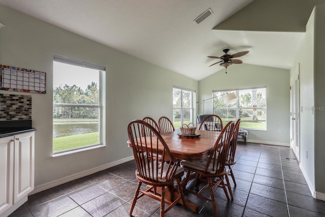 dining area with ceiling fan, dark tile patterned floors, vaulted ceiling, and a healthy amount of sunlight