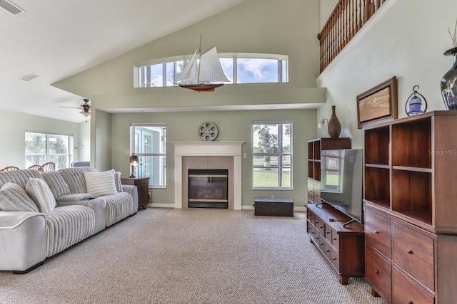 carpeted living room with ceiling fan, a fireplace, high vaulted ceiling, and a healthy amount of sunlight