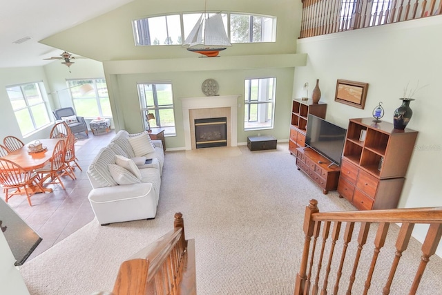 living room with a tiled fireplace, plenty of natural light, and high vaulted ceiling