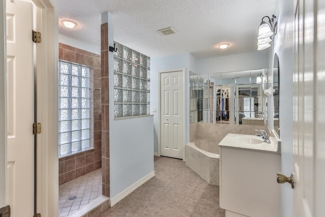 bathroom with vanity, plus walk in shower, a textured ceiling, and tile patterned floors