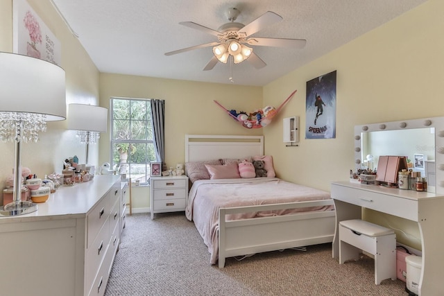 bedroom with ceiling fan, light colored carpet, and a textured ceiling