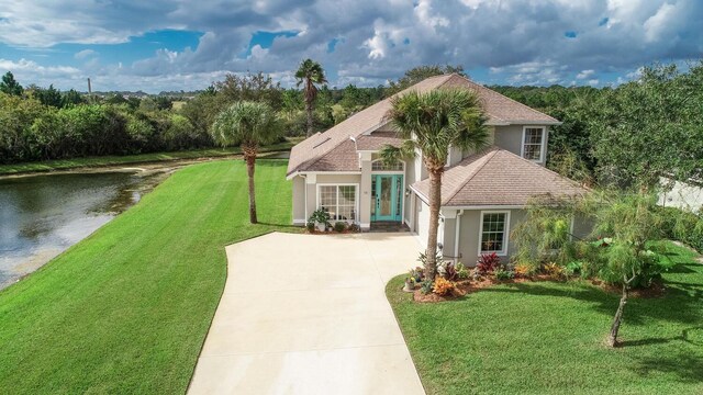 12 S Lakewalk Dr, Palm Coast, FL 32137 - view of front of property with stucco siding, concrete driveway, a front lawn, and a water view