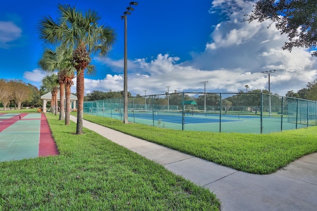 view of tennis court with a lawn