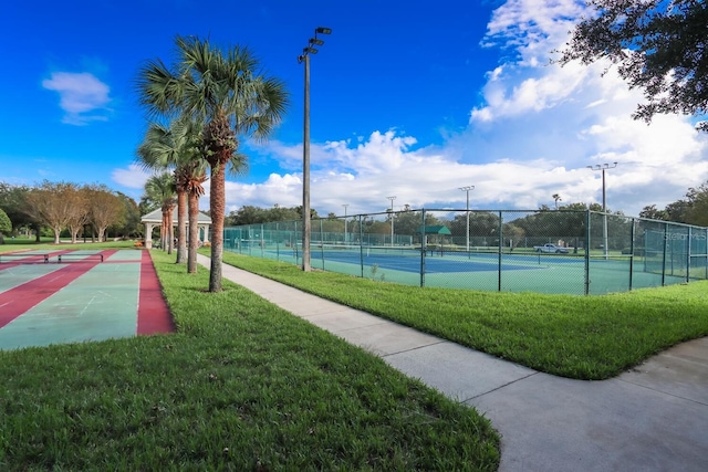 view of tennis court featuring a lawn