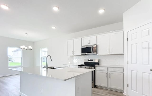 kitchen with an island with sink, appliances with stainless steel finishes, sink, and white cabinetry