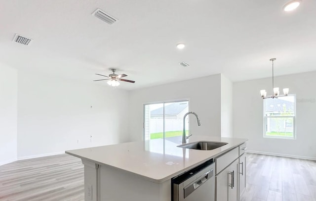 kitchen featuring pendant lighting, dishwasher, light hardwood / wood-style floors, a kitchen island with sink, and sink