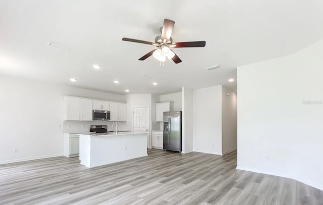 kitchen with light hardwood / wood-style floors, white cabinetry, an island with sink, stainless steel appliances, and ceiling fan