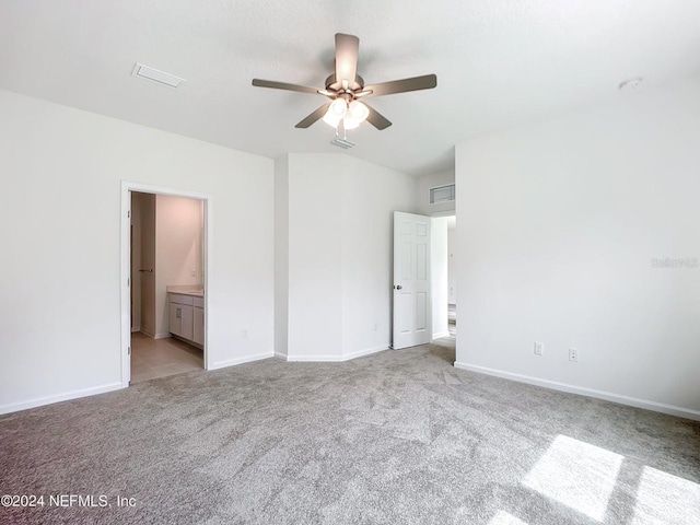 unfurnished bedroom featuring ceiling fan, ensuite bath, and light carpet