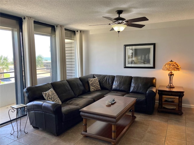 living room with ceiling fan, a textured ceiling, and tile patterned floors