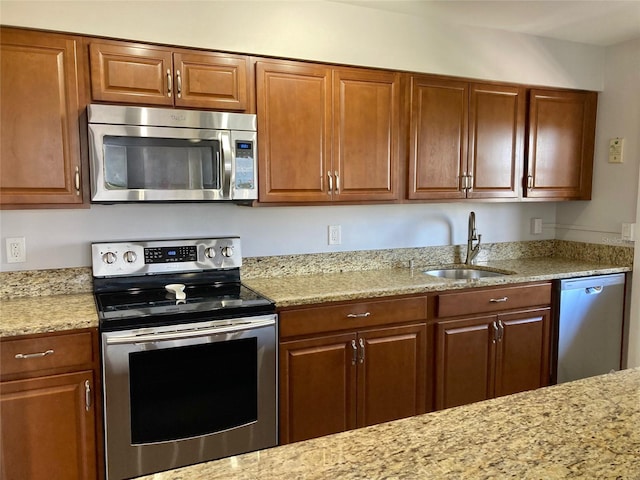 kitchen with light stone countertops, appliances with stainless steel finishes, and sink