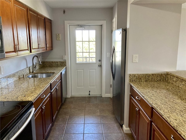 kitchen featuring appliances with stainless steel finishes, light stone countertops, sink, and dark tile patterned flooring