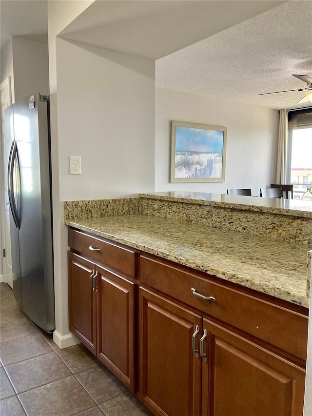 1601 N Central Ave Unit 104, Flagler Beach, FL 32136 - kitchen with a textured ceiling, ceiling fan, light stone countertops, dark tile patterned flooring, and freestanding refrigerator