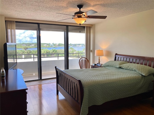 1601 N Central Ave Unit 104, Flagler Beach, FL 32136 - bedroom with access to exterior, wood finished floors, ceiling fan, and a textured ceiling
