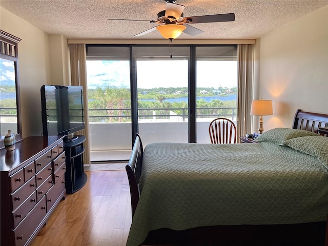 bedroom featuring light wood-type flooring, a textured ceiling, and ceiling fan