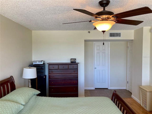 bedroom with ceiling fan, a textured ceiling, and light tile patterned floors