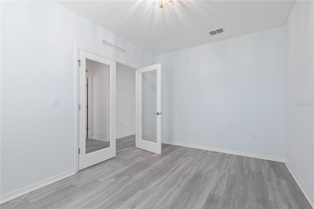 unfurnished room with light wood-type flooring and french doors