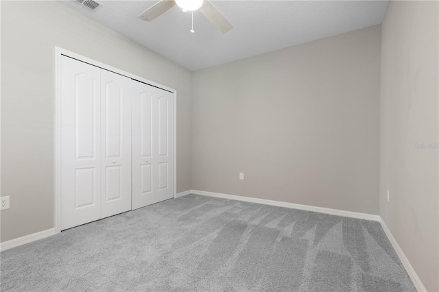 unfurnished bedroom with light carpet, ceiling fan, and a closet