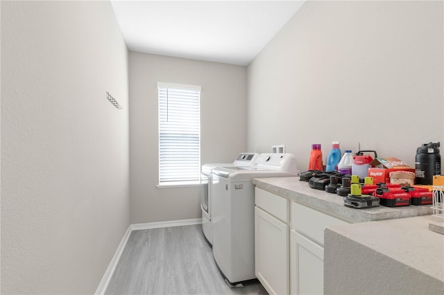 washroom with washing machine and dryer, cabinets, and light wood-type flooring