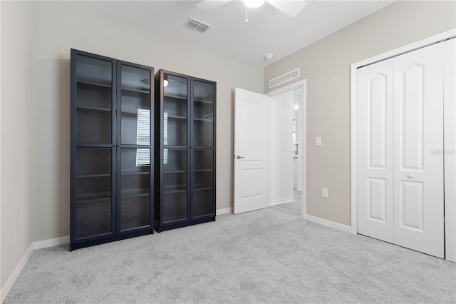 unfurnished bedroom featuring ceiling fan, a textured ceiling, and light carpet