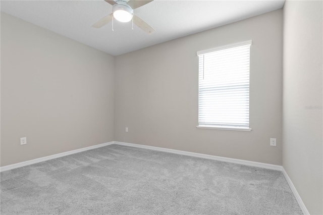 carpeted spare room featuring ceiling fan and baseboards