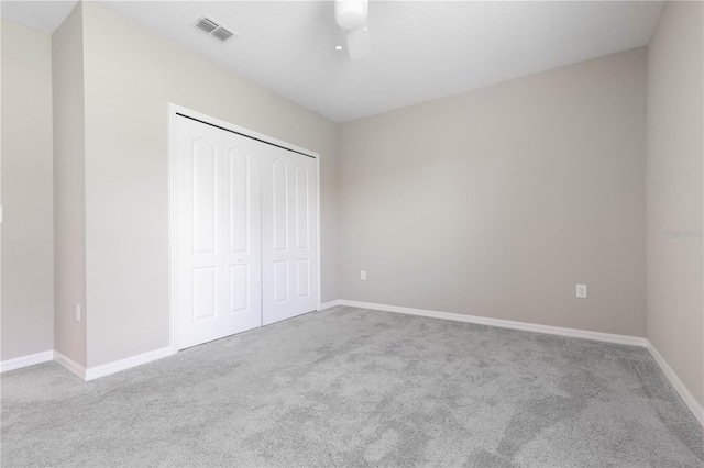 unfurnished bedroom featuring a closet, light colored carpet, and ceiling fan