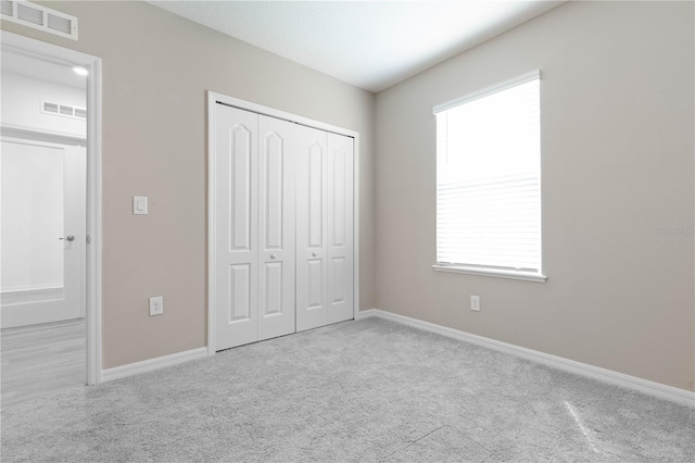 unfurnished bedroom with a closet and light colored carpet