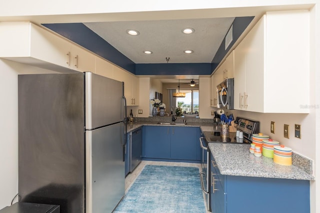 kitchen featuring blue cabinets, dark stone countertops, sink, stainless steel appliances, and hanging light fixtures